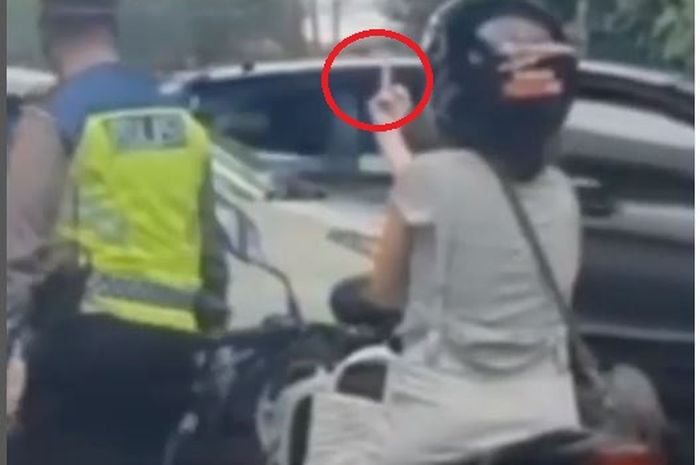 Pengendara wanita naik Yamaha X-Ride acungkan jari tengah usai ditegur agar mengenakan helm di kolong flyover Pasar Rebo, Ciracas, Jakarta Timur