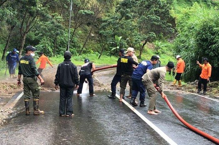 Tim gabungan membersihkan material longsor yang menutup badan di Jalan tembus Tawangmangu-Magetan, Senin (7/2/2022).