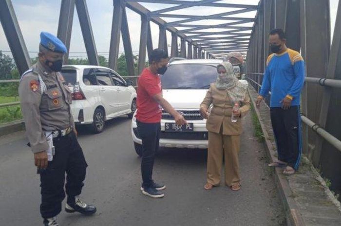 Polisi bersama Bu guru yang mengaku jadi korban begal tapi ternyata bohong di atas jembatan desa Tanjangrono, Ngoro, Mojokerto, Jawa Timur