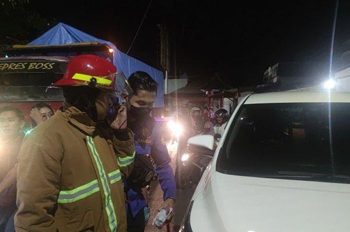 Petugas damkar dan warga saling bantu buat menyelamatkan bocah yang terkunci di dalam Toyota Kijang Innova, Jumat (13/05/2022).