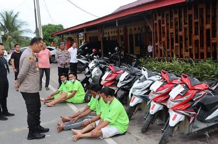 Lima orang sindikat pencurian motor duduk dengan wajah tertunduk dan tangan diborgol di depan barang bukti tujuh motor di Polres Aceh Timur