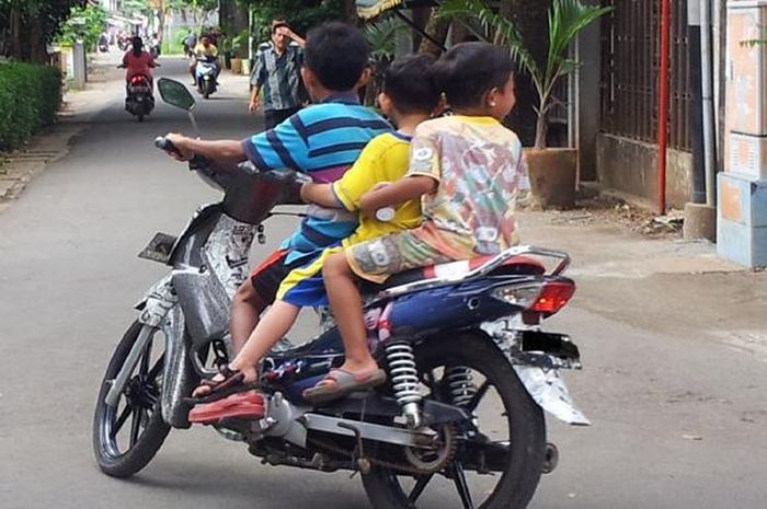 ilustrasi - Anak di bawah umur yang mengendarai motor berbonceng tiga tanpa menggunakan helm.