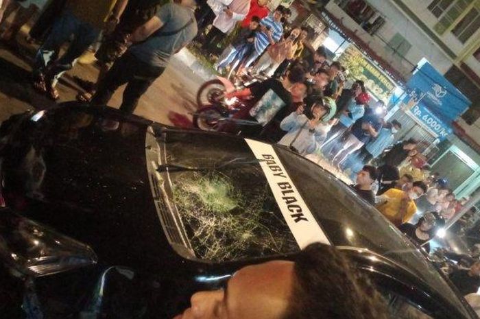 Warga dan pengendara melihat kondisi mobil Toyota Agya hitam yang hancur dirusak massa karena terlibat kecelakaan lalu lintas di kawasan Bengkong, Kota Batam, Provinsi Kepulauan Riau (Kepri), Minggu (19/6/2022) sekira pukul 23.00 WIB.