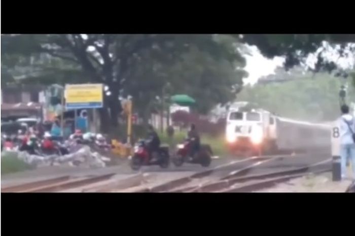 Tangkapan layar video tiga pengendara motor trabas palang pintu kereta api dan hampir tertabrak