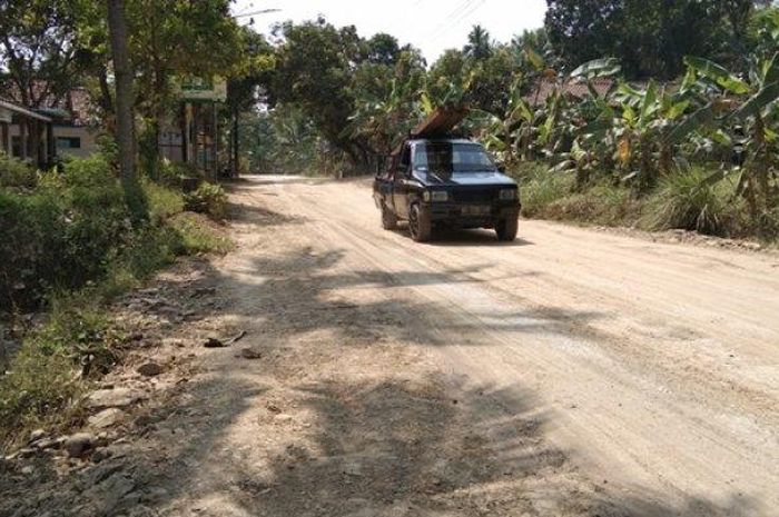 Satu unit mobil melintas di jalan desa yang rusak karena dilalui truk pembawa tanah urug Tol Yogyakarta-Solo.