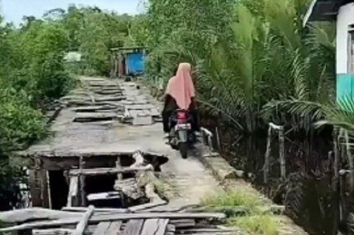 Pengendara Honda BeAT yang melintas di sebuah jembatan di Indragiri Hilir, Riau.