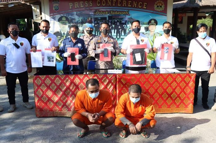 Kedua tersangka duduk jongkok saat rilis pengungkapan kasus penipuan online di Mapolsek Sukawati, Gianyar, Bali, Rabu (27/7/2022). 