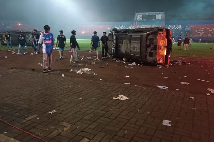 Dua unit mobil polisi terkapar di tengah Stadion Kanjuruhan usai kerusuhan yang dilakukan suporter Arema pada Sabtu (1/10/2022).