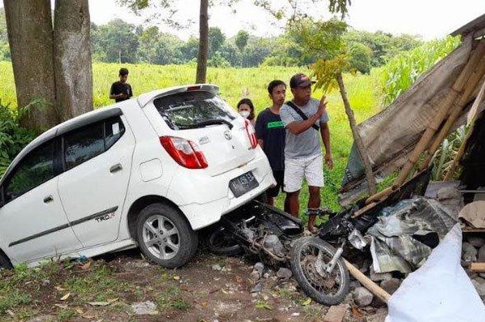 Toyota Agya terjungkal ke selokan usai menghantam keras pasutri duduk di atas Honda Supra X di Plosoklaten, Kediri, Jawa Timur