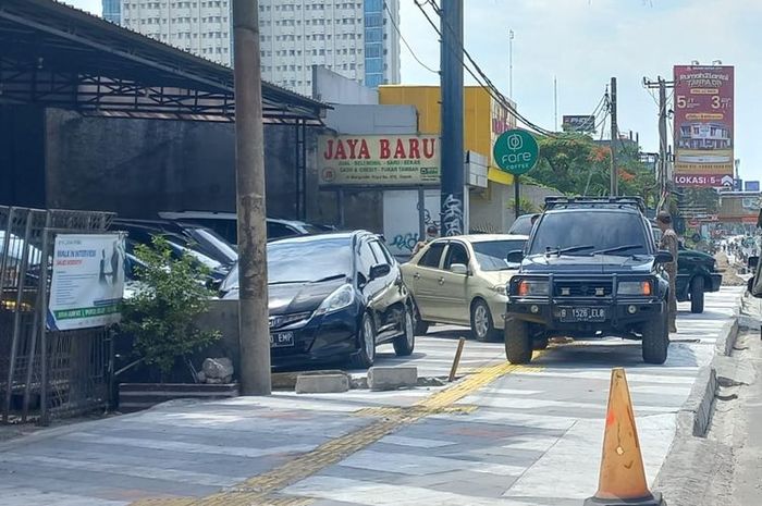 Beberapa unit dagangan showroom mobil bekas parkir di atas trotoar jalan Margonda Raya, Depok yang tengah direvitalisasi