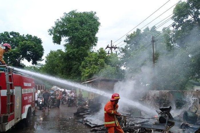 Petugas Damkar tengah memadamkan api yang membuat ludes toko jok motor dan warung di Kabupaten Proboliggo (30/11/2022).