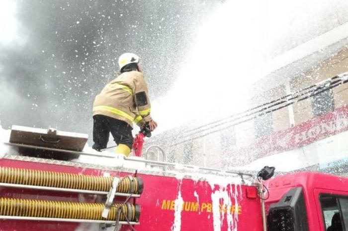 Personel Damkar Jakarta Timur saat proses pemadaman api pada dealer Honda yang terbakar, Cakung, Jumat (9/12/2022). 