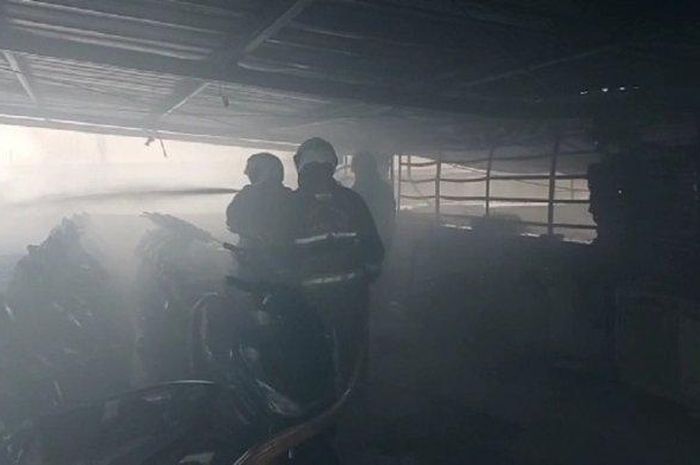 Personel Damkar Jakarta Timur saat proses pemadaman api pada dealer Honda yang terbakar, Cakung, Jumat (9/12/2022)