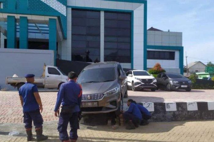 Damkar Cibinong evakuasi Suzuki Ertiga yang tersangkut pembatas parkiran dan jalan di kantor Disdukcapil kabupaten Bogor, Jawa Barat