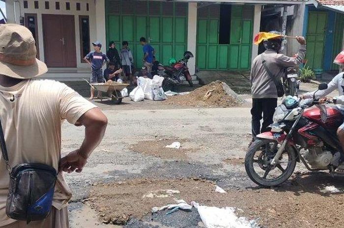 Para pemuda di Undaan, Kudus bergotong royong menambal jalan yang berlubang yang di danai dari donasi.