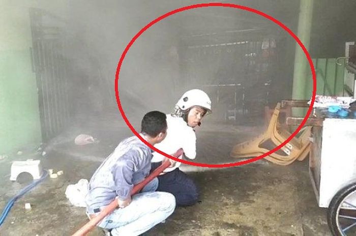 Dalam lingkaran merah, Toyota Kijang Innova disembur air pemadam kebakaran Gresik karena berasap putih lalu disusul api usai dipakai jalan-jalan pemilik