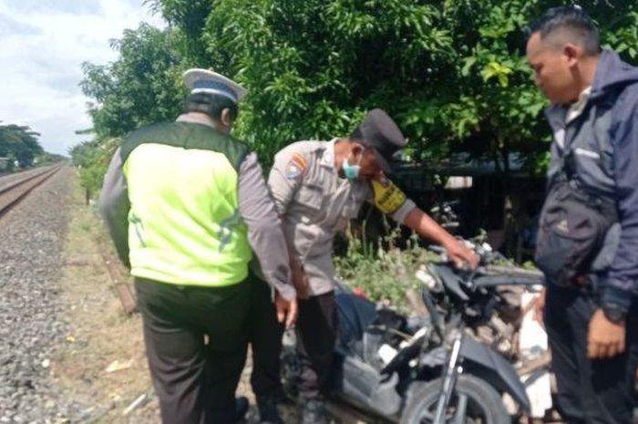 Polisi mengevakuasi bangka Honda Vario 110 yang hancur ditemper kereta api barang di desa Moropelang, Babat, Lamongan
