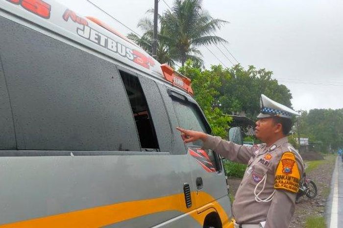 Polisi menunjukan kaca jendela mobil Travel Isuzu Elf yang dibuka salah satu penumpang untuk loncat di jalan saat melaju di jalan raya Kalibaru, Banyuwangi