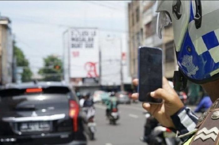 Anggota Polisi memfoto Mitsubishi Pajero Sport yang melakukan pelanggaran lalu lintas