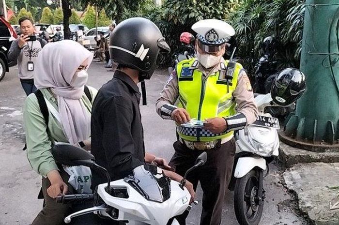 Polisi menilang pengendara motor saat razia Operasi Patuh Jaya 2023 di Kebayoran Baru, Jakarta Selatan