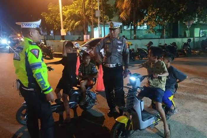 Ilustrasi anak-anak pengendara sepeda listrik yang berkendara di jalan raya.
