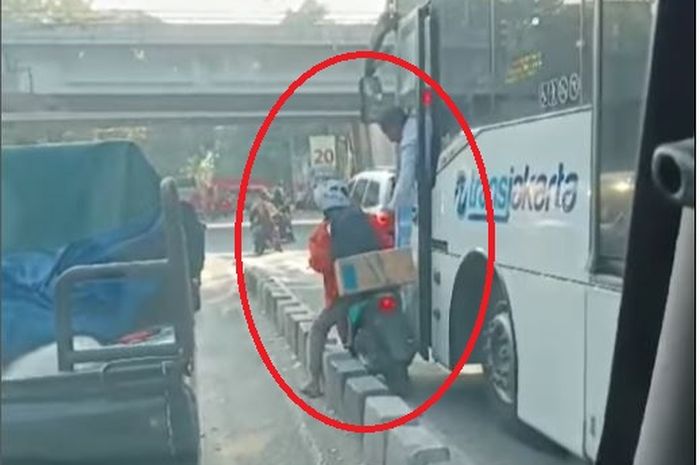 Dalam lingkaran merah, sopir bus TransJakarta emosi ke pemotor yang kejepit antara bus dan separator