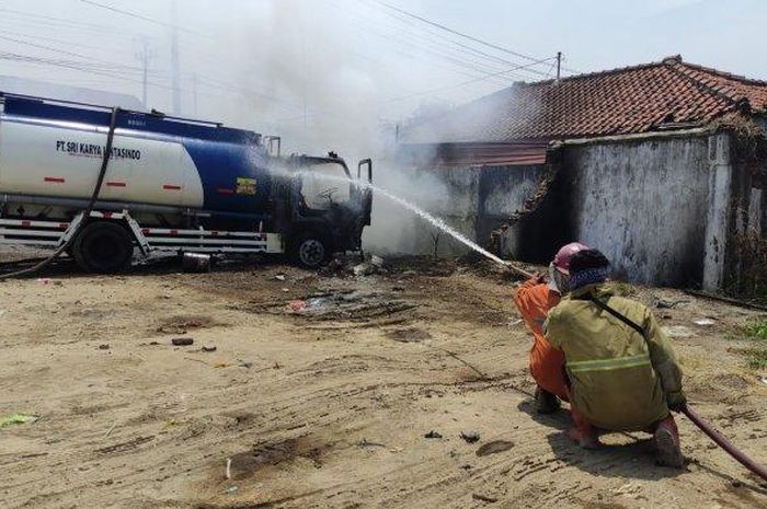 Petugas pemadam kebakaran semprotkan air untuk memadamkan api yang membakar truk tangki BBM PT Sri Karya Lintas Sindo