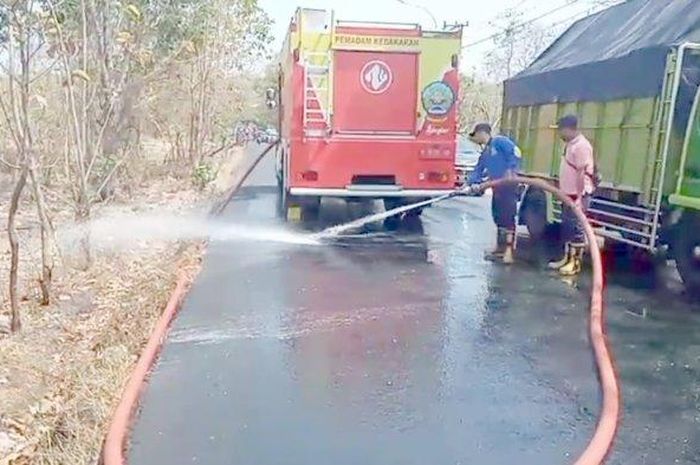 Anggota pemadam kebakaran menyemprot aspal jalan di Paterongan, Galis, Bangkalan, Madura bekas terkena tetesan air garam karena licin di 