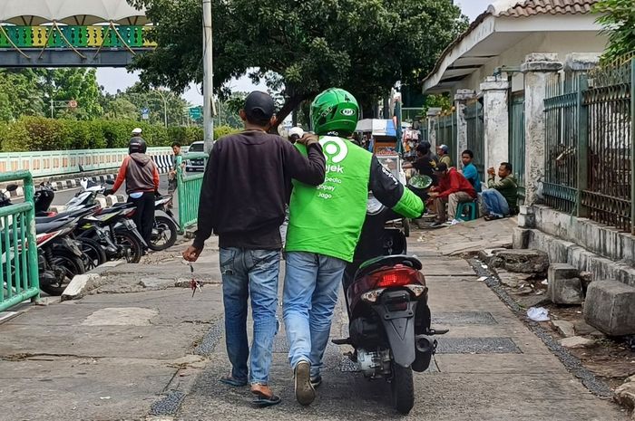 Pengendara ojek online akting tuntun motor di atas trotar demi bisa lawan arah di dekat stasiun Pasar Minggu