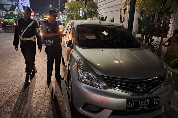 Petugas gabungan menggembosi dan menggembok ban mobil yang nekat parkir di sepanjang jalan Pasar Kembang Jogja