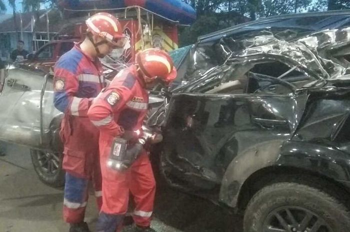 Tim Damkar kota Bogor memotong bodi Toyota Fortuner yang ringsek tabrak truk di tol Jagorawi