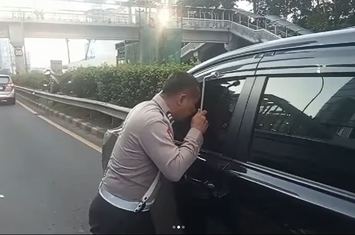 Anggota Polisi melihat ke dalam kabin Toyota Kijang Innova Reborn yang berhenti di lajur kanan tol Dalam Kota Jakarta, (9/8/24)