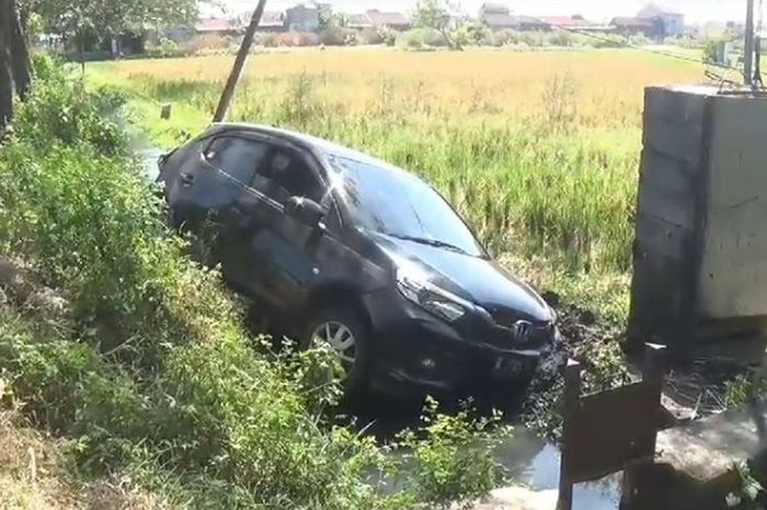 Honda Brio terlempar ke comberan tepi sawah akibat ditabrak bus PO Sugeng Rahayu dari belakang di jalan raya Ngawi-Maospati, desa Geneng, Ngawi, Jawa Timur