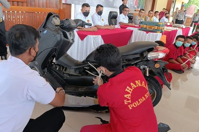 MR (24) memperagakan caranya menyembunyikan 4,9 kg sabu dan 5.000 pil ekstasi di balik bodi Yamaha NMAX 155 di Polda NTB