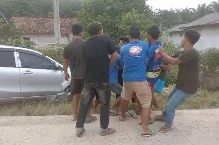 Warga beramai-ramai menarik Toyota Avanza yang terperosok ke selokan di jalan raya desa Eka Mulya, Mesuji, Lampung