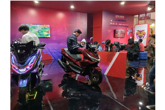 Pengunjung bermain game ponsel sembari mencoba kenyamanan Honda PCX&nbsp;edisi Cyber Trance 