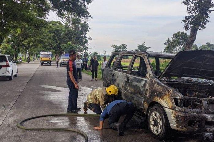Petugas pemadam kebakaran memadamkam api yang membakar Isuzu Panther milik seorang guru saat dibawa berangkat mengajar di jalan raya Padangan-Plemahan, Kayen Kidul, kabupaten Kediri