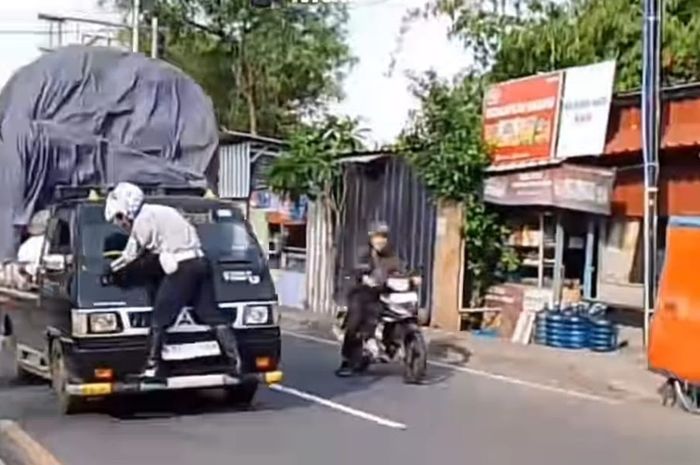Petugas Dishub Depok bergelantungan di depan Mitsubishi L300 yang menolak diperiksa di Jalan Raya Bogor, Cilodong, Depok, Jawa Barat.