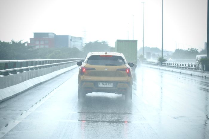 ILUSTRASI. Mitsubishi XForce melaju di jalan tol saat hujan deras.
