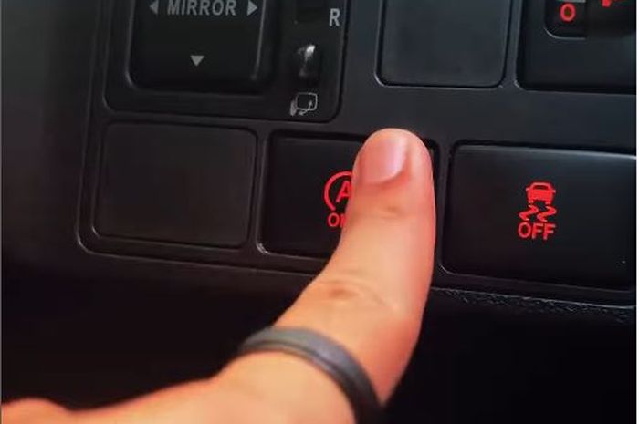 Pengemudi memencet tombol fitur Idling Stop System pada mobil