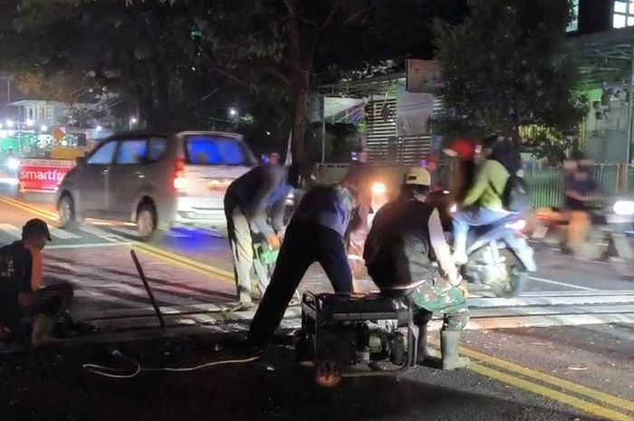Proses pembongkaran polisi tidur yang baru dipasang belum genap seminggu di jalan raya Pandaan, Pasuruan, Jawa Timur