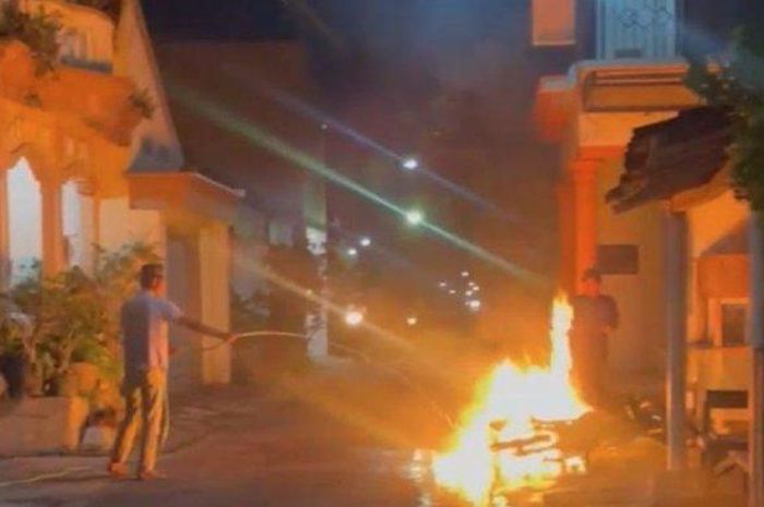 Warga berusaha memadamkan api yang membakar motor di Jalan Soroito, Patihan, Ponorogo, Jawa Timur, (9/22/5) malam karena pemilik memperbaiki sambil merokok
