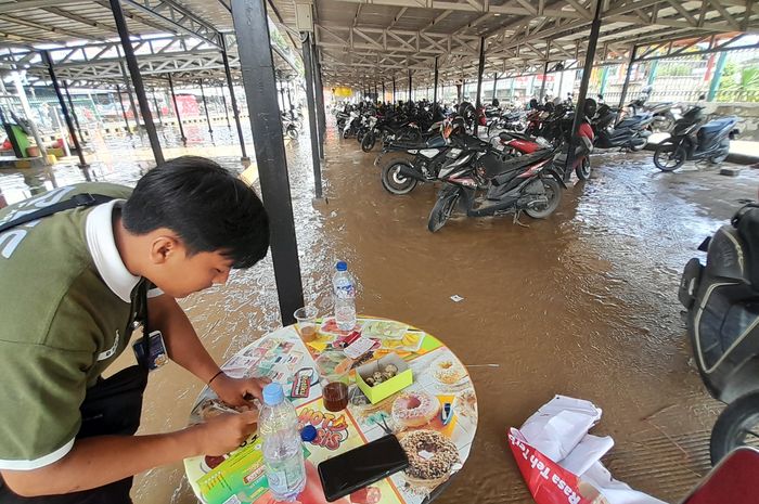 Petugas parkir di Stasiun Bekasi menunggu pemilik motor terendam banjir