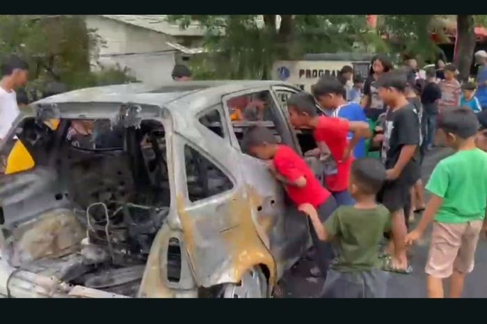 Warga yang mayoritas anak-anak mengerubuti bangkai Mercedes-Benz A140 usai terbakar habis di wilayah Klender, Duren Sawit, Jakarta Timur, (3/3/25)