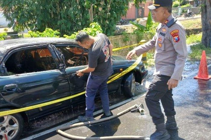 Suzuki Baleno nopol DK 1933 AAC digaris Polisi setelah terbakar saat melaju di jalan raya Cluring, kabupaten Banyuwangi, Jawa Timur