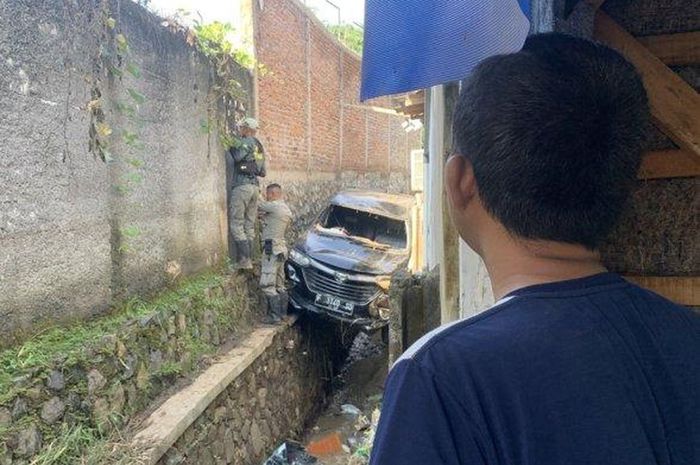 Daihatsu Xenia milik Yanto Suryanto (46) warga perumahan Puncak Manis, desa Selajamber, Sukaluyu, kabupaten Cianjur tersangkut di atas selokan dan tergencet di antara dua tembok