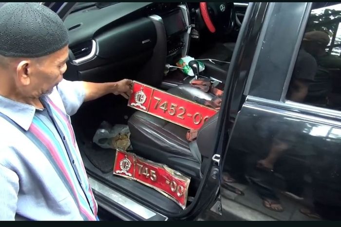 Warga menunjukan pelat nomor dinas Lemhanas 7452-00 yang dipakai Toyota Fortuner yang menjadi penyebab kecelakaan beruntun di depan Halte Utan Kayu Rawamangun, Jakarta Timur