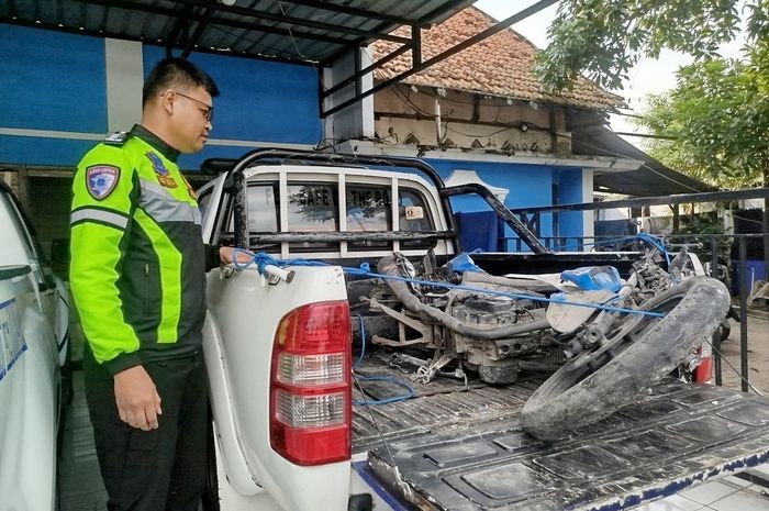 Polisi menunjukan Honda MegaPro milik pegawai PLN yang masuk kolong bus AKAS usai bertabrakan di jalan raya desa Rosep, Blega, Bangkalan, Madura, Jawa Timur, (15/7/25)