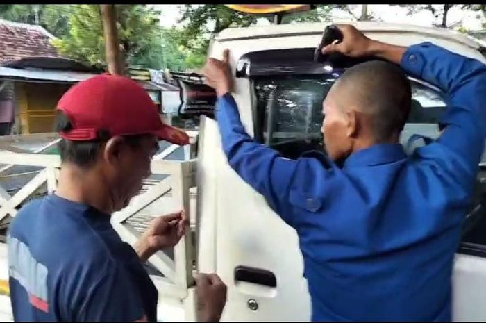 petugas pemadam kebakaran Pamekasan berusaha membuka pintu Daihatsu Gran Max yang terkunci dari dalam
