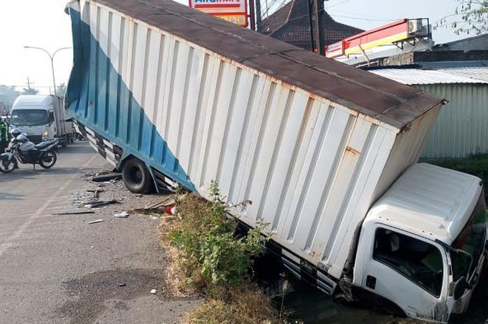Truk Boks Isuzu Elf NMR tersungkur ke dalam selokan akibat dihantam belakang bus PO MIRA nopol S 1818 US